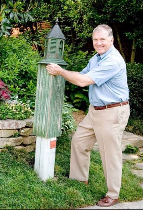 A Man Leaning Against A Green Post In The Grass