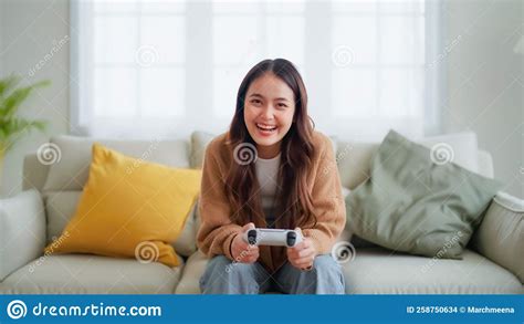 Young Asian Woman Sitting In Living Room Sofa Holding Joystick Stock
