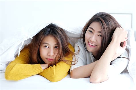 Lgbt Young Cute Asia Lesbians Lying And Smiling On White Bed Together
