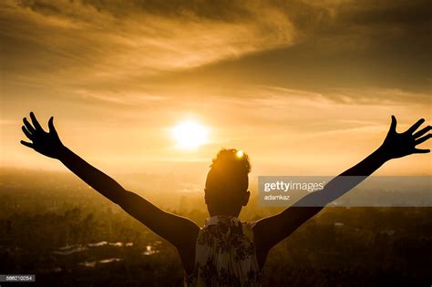 African American Woman Raising Arms At Sunset High Res Stock Photo