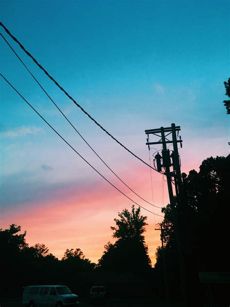 The Sun Is Setting Behind Power Lines And Telephone Poles In Front Of