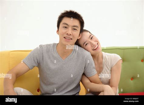Couple Sitting And Facing Camera Woman Hugging Mans Arm Stock Photo