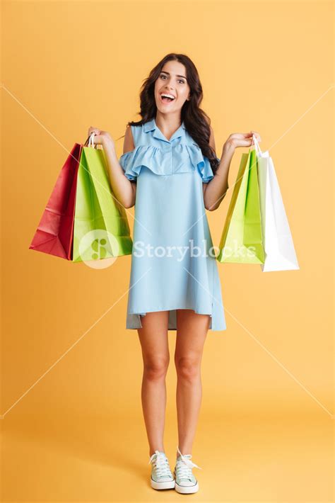 Full Length Portrait Of A Smiling Casual Girl Holding Shopping Bags