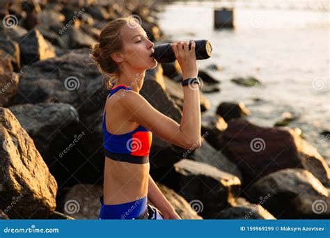 Beautiful Woman Drinking A Water From Bottle Sitting On Sea Stones Stock Image Image Of