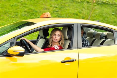 Photo Of Blonde Female Driver Sitting In Yellow Taxi On Summer Stock