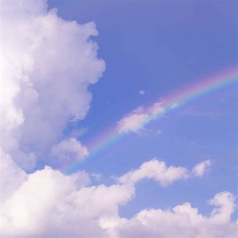 A Rainbow In The Sky With Clouds And Blue Sky Behind It On A Sunny Day