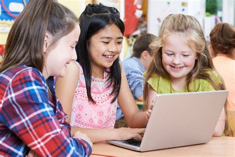 Group Of Elementary School Children Working Together In Computer Stock