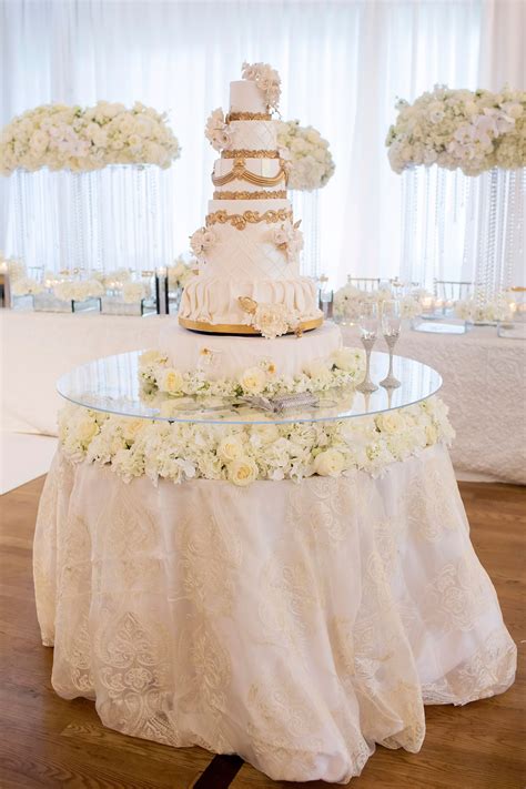 A Wedding Cake Sitting On Top Of A Table Covered In White Flowers And