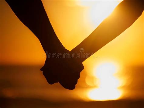 Closeup Of An Silhouette Couple Holding Hands At The Beach During A