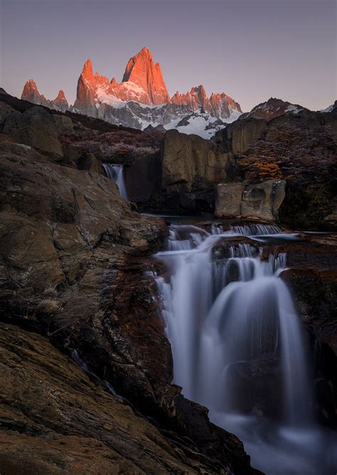 The Flow Of Light A Waterfall Gently Flows Under Mount Fitz Roy