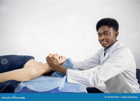 African American Man Masseur Conducting Anti Aging Treatment Facial Massage For Young Female
