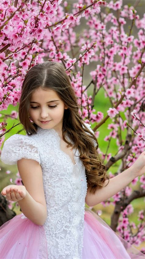 Cute Little Girl Is Standing Between Cherry Blossom Pink Flower Trees