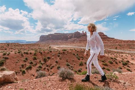 A Curly Haired Blonde Man Posing Around The Famous Buttes Of Monument