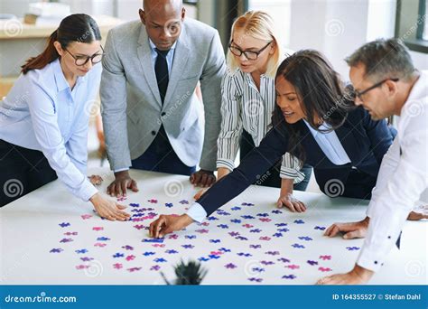 Diverse Group Of Businesspeople Working Together To Solve A Puzz Stock