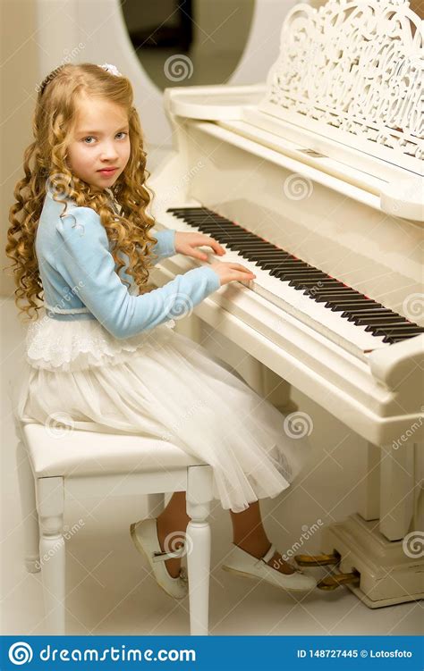 Beautiful Little Girl Is Playing On A White Grand Piano