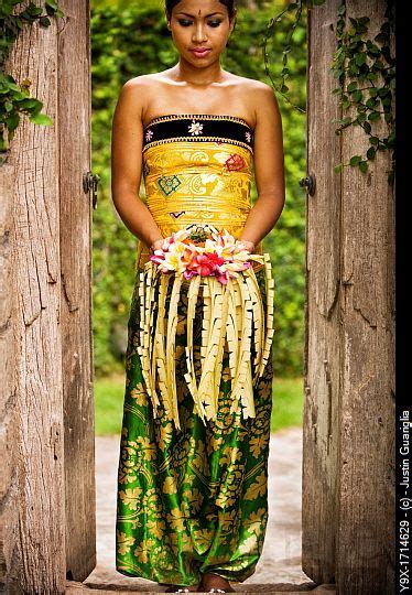 A Balinese Woman Holding A Floral Arrangement Dress In A Traditional