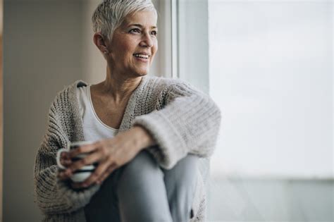 Happy Mature Woman Relaxing By The Window During Coffee Time Stock