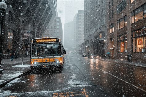 A Bus Driving Down The Road In A Populous City During A Winter Snowfall