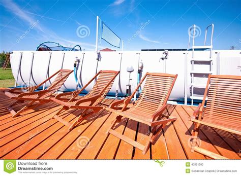 A deckchair (or deck chair) is a folding chair, usually with a frame of treated wood or other material. Swimming Pool Deck Chairs Stock Photo - Image: 43521380