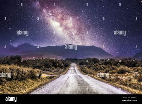 Countryside Road With Mountains And The Milky Way Galaxy Stock Photo