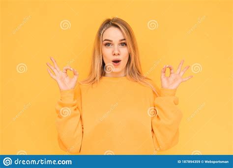 Amazed Girl In Orange Clothing Shows A Gesture Ok In Her Hands Looking
