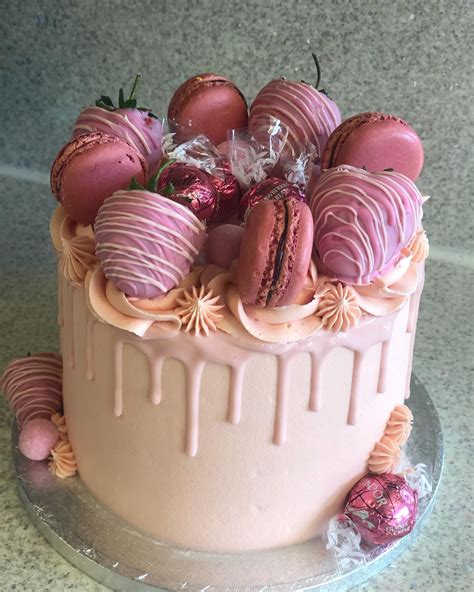pretty pink drip cake topped with pink dipped strawberries and macarons and pink lindt 💗