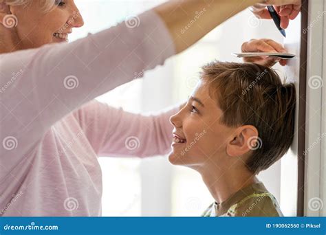 Mother Measuring The Height Of Her Son Against Wall Stock Photo Image