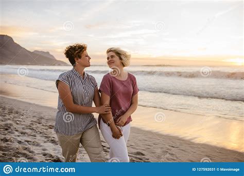Smiling Lesbian Couple Enjoying A Romantic Walk Along A Beach Stock Image Image Of Nature