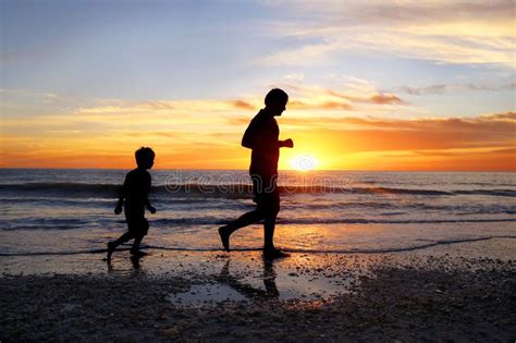 Silueta Del Padre Y Su Hijo Joven Que Activa En La Playa Junto En La
