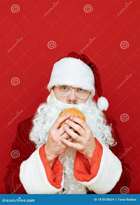 Santa Claus In Red Costume And Beard Isolated On Red Background Holds