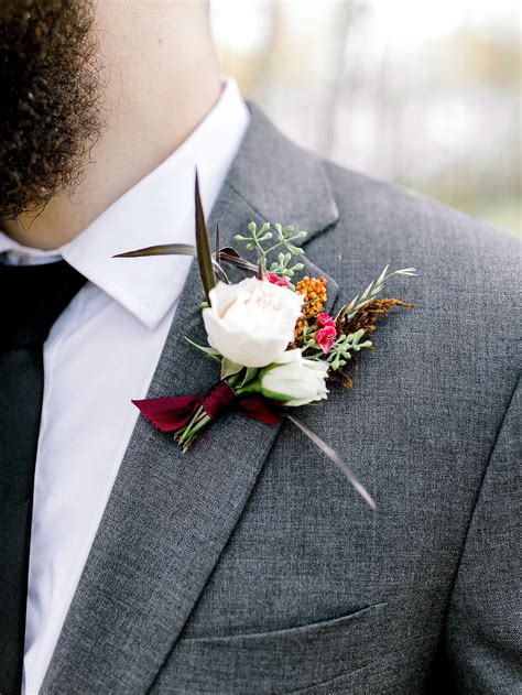 A Man Wearing A Suit And Tie With A Boutonniere On His Lapel