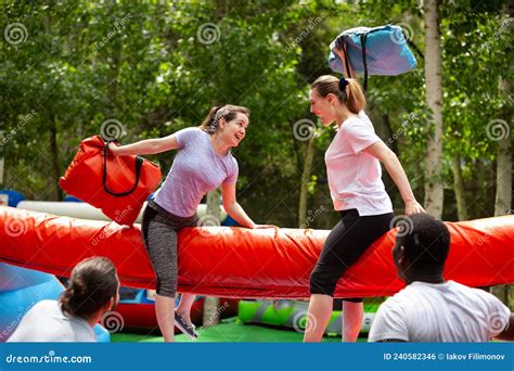 Cheerful Girlfriends Fighting With Inflatable Pillows In An Amusement
