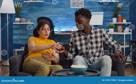 Pregnant Interracial Couple Sitting On Living Room Sofa Stock Photo