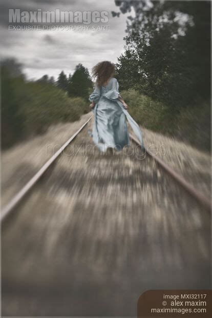 Photo Of Woman Running Away Along Railroad Tracks In A Long Dress