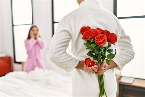 Man Surprising His Girlfriend With Bouquet Of Roses At Bedroom Stock