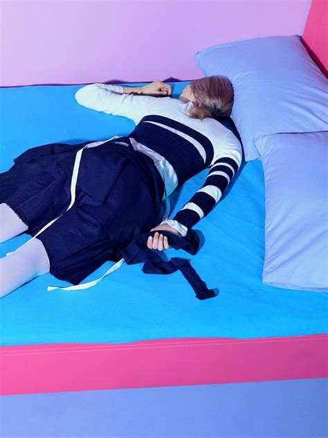 A Woman Laying On Top Of A Blue Bed In A Room With Pink And Blue Walls