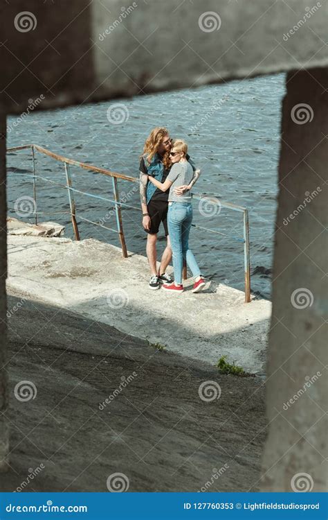 Novio Tatuado Y Novia Elegante Que Abrazan En El Puente Imagen De