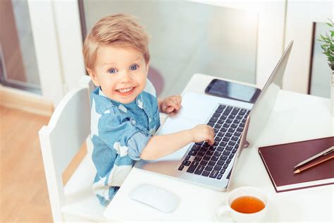 Little Business Blond Baby Boy In Blue Shirt Sitting At A Computer