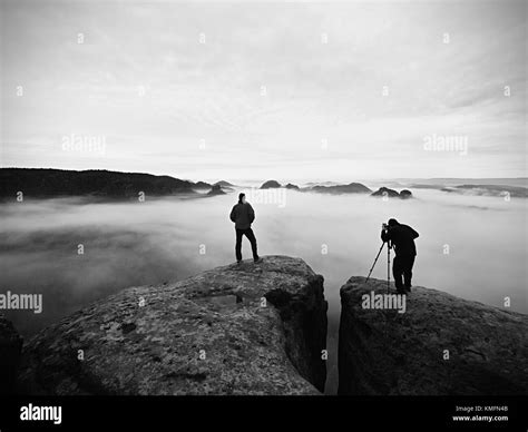 Artist Photographer Works With Tripod On Cliff Above Clouds Dreamy