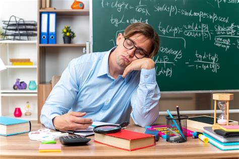 Joven Profesor Con Gafas Cansado Y Aburrido Quiere Dormir Sentado En El Escritorio De La Escuela