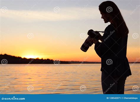 Young Female Photographer Holding Professional Camera On Riverside