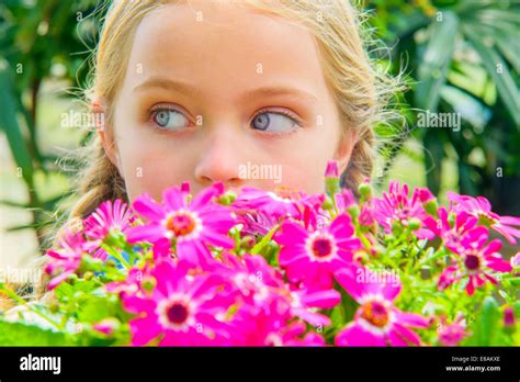 Close Up Portrait Of Girl Looking Sideways Behind Pink Flowers Stock