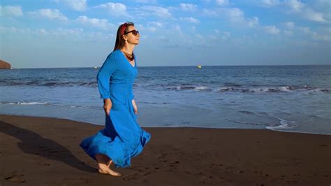 Portrait Of A Woman In A Beautiful Blue Dress On A Black Volcanic Beach Slow Motion 23143964