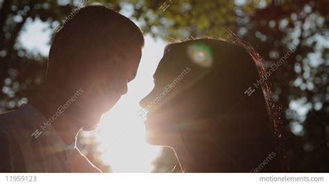 A Loving Couple Hugs And Kisses Against The Backdrop Of Sunset The