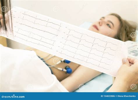 The Doctor Cardiologist Looks At The Printout Of The Cardiogram Of Patients Which Lies On The