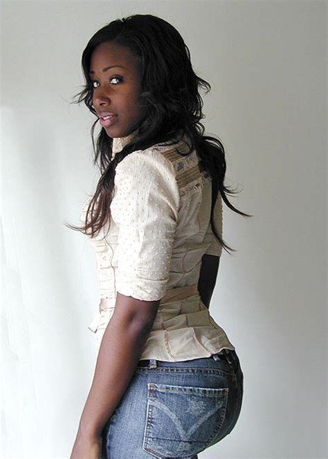 A Woman In Jeans And A White Shirt Is Posing For The Camera With Her