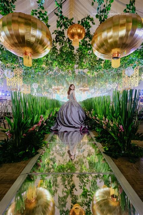 A Woman In A White Dress Is Sitting On The Ground Surrounded By Plants And Lights
