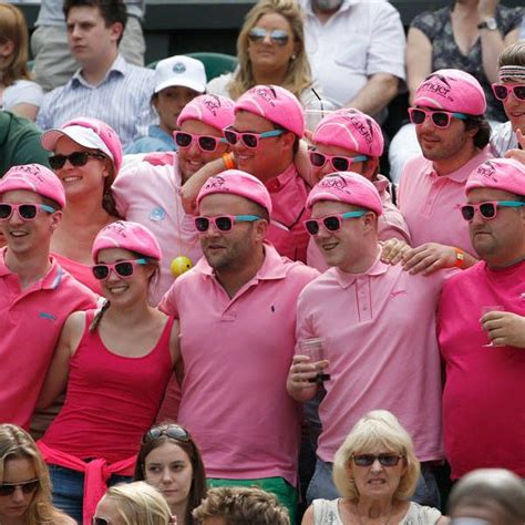 Spectators Dressed In Pink Stand On Centre Court At The Wimbledon Tennis Championships In