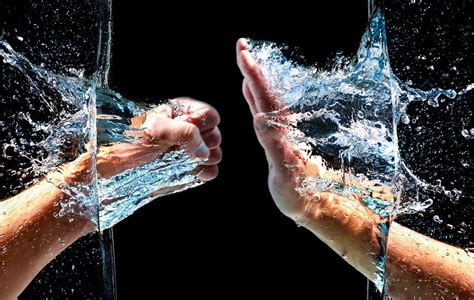 Two Hands Reaching Out To Each Other Through Water Splashing From The