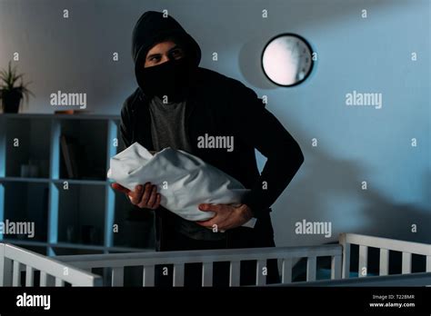 Kidnapper In Black Mask Holding Infant Child Near Crib Stock Photo Alamy